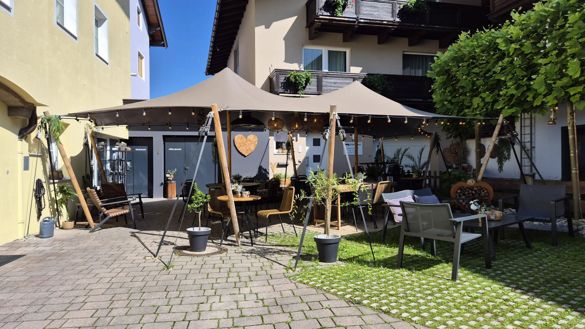 Gemütlicher Außenbereich eines Cafés mit Sonnenschirmen und Pflanzen.