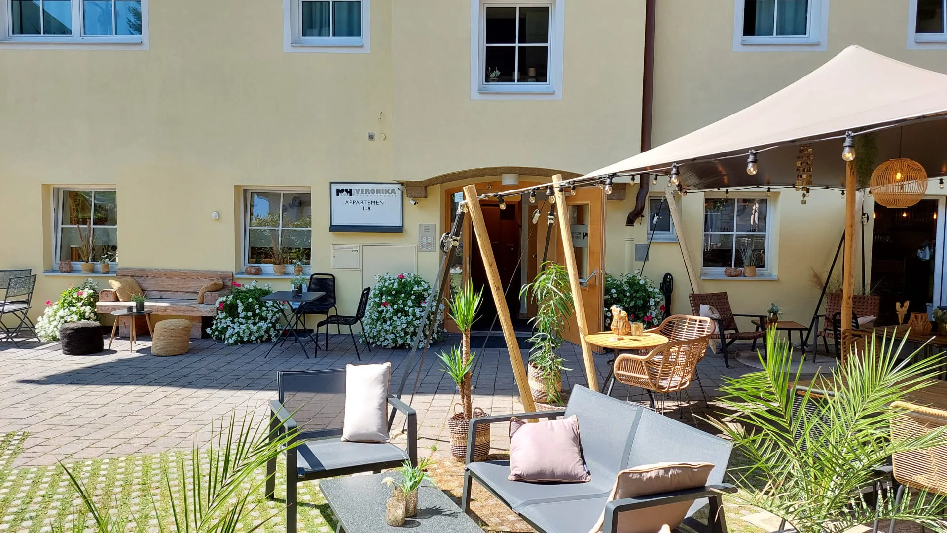 Hinterhof mit Gartenmöbeln und Sonnenschirm vor gelbem Gebäude