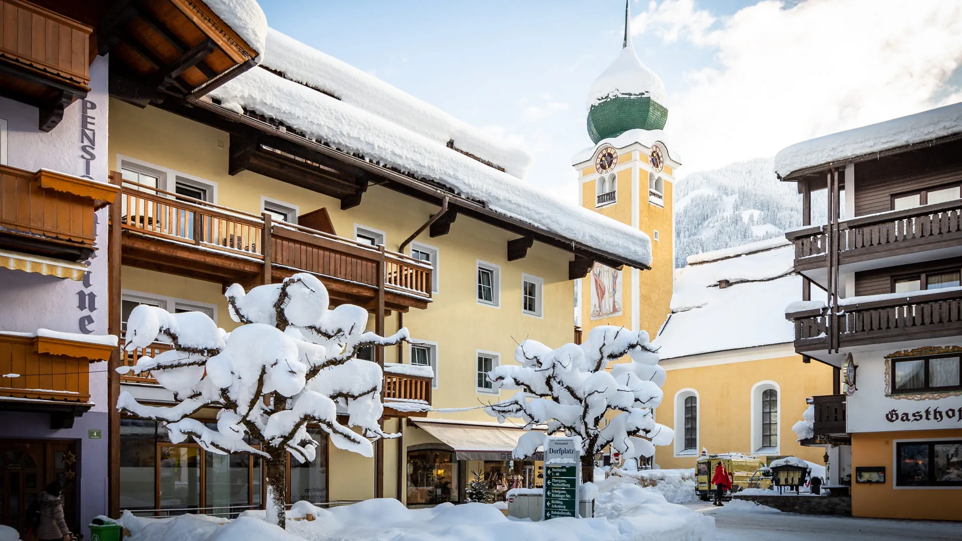 Winterliche Landschaft mit schneebedeckten Gebäuden und Bäumen.